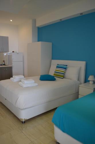 a white bed in a room with a blue wall at Ammos Beach in Glífa