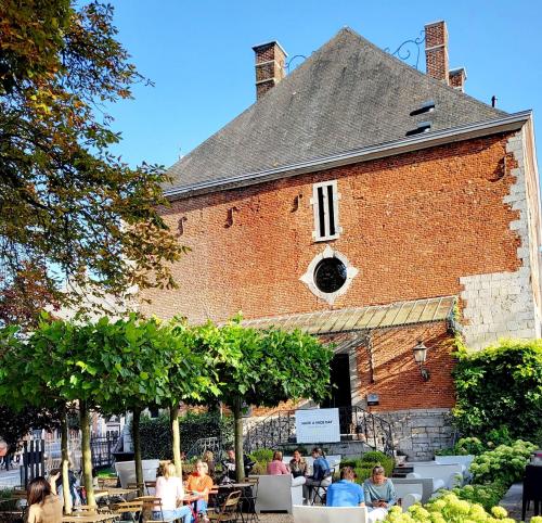 a group of people sitting at tables outside of a building at Hôtel Le Manoir in Marche-en-Famenne
