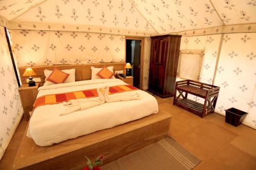 ジャイサルメールにあるRomiyo Desert Campのテント内の大型ベッド付きのベッドルーム1室
