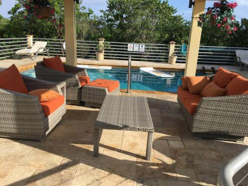 um grupo de cadeiras e mesas ao lado de uma piscina em Just Chillin in Little Cayman em Head of Bay