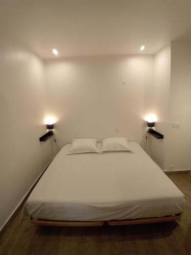 een groot wit bed in een kamer met 2 verlichting bij 11 rue Vauban in Antibes
