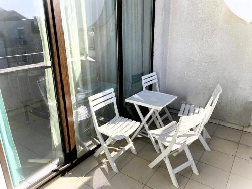 two white chairs and a table on a balcony at Private apartments Stamopolu lux in Primorsko