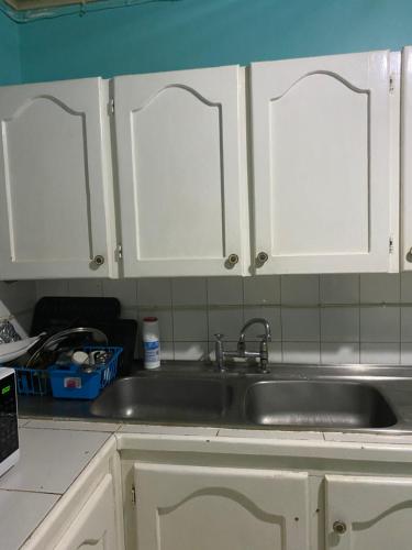 a kitchen counter with a sink and white cabinets at Fairmont in Negril