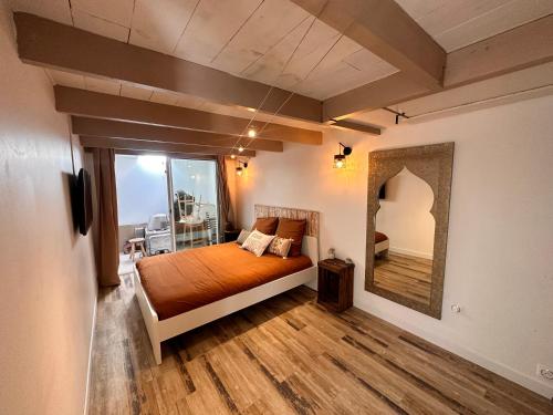 - une chambre avec un lit orange et un grand miroir dans l'établissement Maison provençale au bord de l’eau, à Istres
