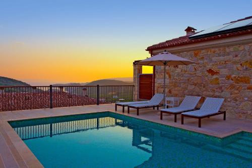 a swimming pool with two chairs and an umbrella at Salvator Villas & Spa Hotel in Parga