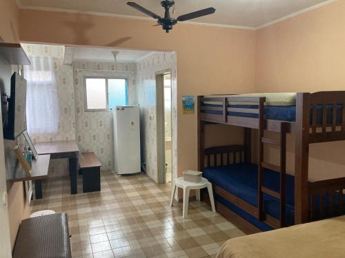 a bedroom with bunk beds and a desk and a refrigerator at Kitnet Cantinho 26 in Mongaguá