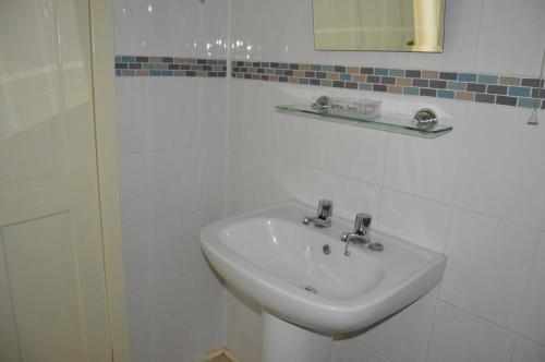 a white bathroom with a sink and a mirror at Kirk View holiday apartment in Kirkcaldy