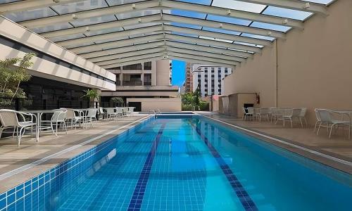 a large swimming pool with chairs and tables on a building at Flat Excelente em frente ao aeroporto de Congonhas - H1216 in São Paulo