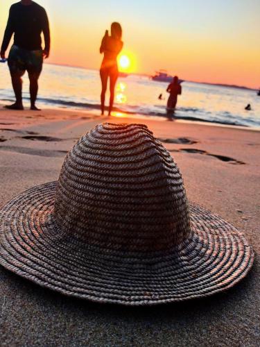 um chapéu de palha sentado na praia enquanto o sol se põe em Erva Cidreira Hostel em Salvador