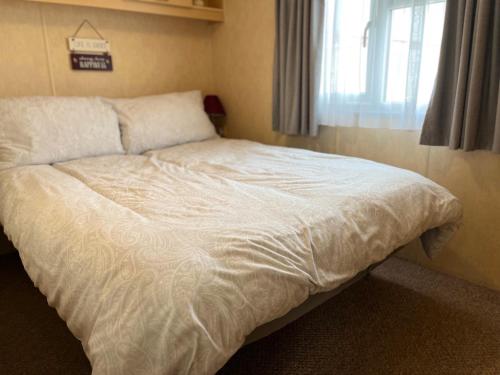 a large bed in a bedroom with a window at Golden Sands 6 Berth Beach front Ingoldmells beds made up for arrival WIFI in Ingoldmells