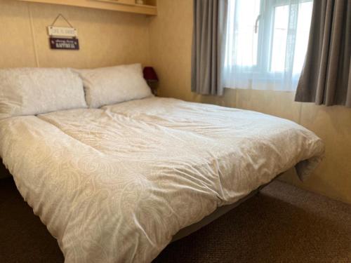 a large bed in a bedroom with a window at Golden Sands 6 Berth Beach front Ingoldmells in Ingoldmells