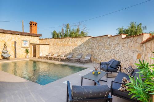 una piscina con sillas y una pared de piedra en Villa Miromar en Pula