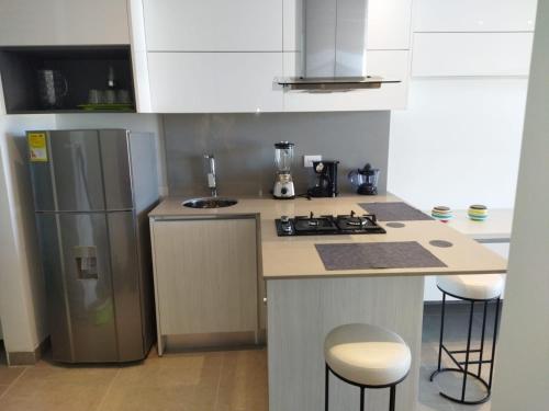 a kitchen with a refrigerator and a counter with stools at Distrito 90 in Barranquilla