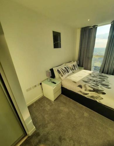 um quarto com uma cama e uma grande janela em Luxurious 3 Bedroom Flat Close To East Croydon Station - Gym - Sleeps 6 em Londres