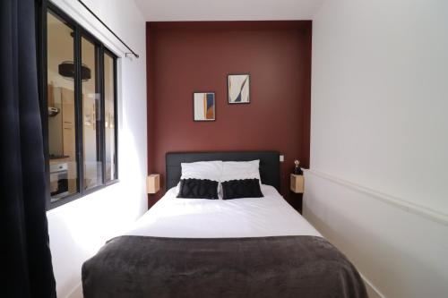 a bed in a room with a red wall at Le Patio - Spacieux et lumineux T3 - 15 min centre pieds in Bergerac