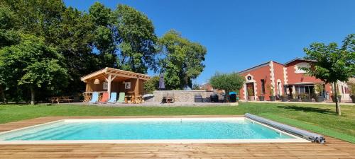 une piscine dans une cour à côté d'une maison dans l'établissement DOMAINE DES PIERRES PRECIEUSES - Demeure de Charme - Grand Standing - 15 pers - Spa - Massages - Détente et Bien-être - 30' Bordeaux, à Gauriaguet