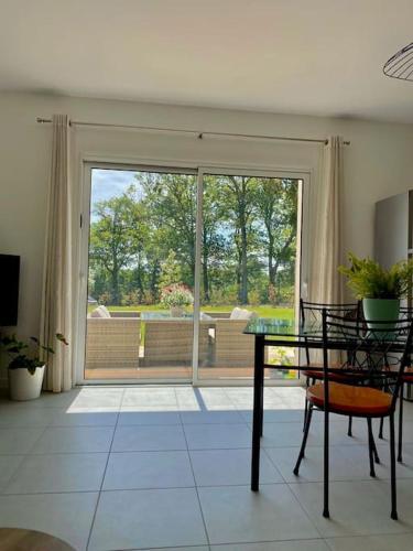 d'un salon avec une table en verre et une porte coulissante en verre. dans l'établissement Repos et détente au coeur des vignes, à Lignan-de-Bordeaux
