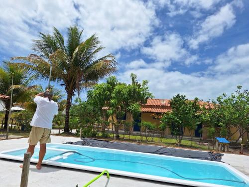 un hombre parado en un poste junto a una piscina en Casas lindas no paraiso!, en Costa Dourada