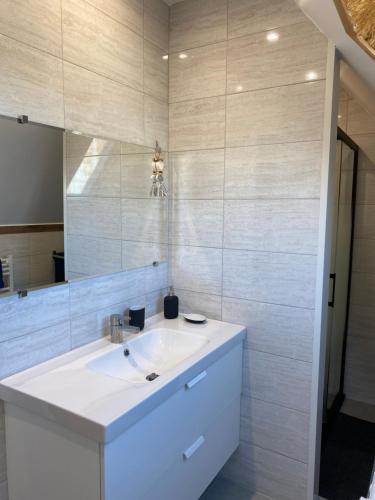 een badkamer met een witte wastafel en een spiegel bij LA CASA in Olby