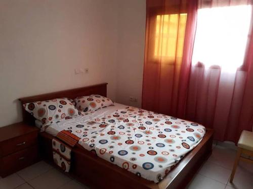 a small bedroom with a bed with a floral comforter at Villa AV Lomé in Lomé