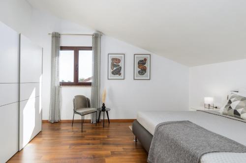 a white bedroom with a bed and a chair at Villa Miromar APP in Pula