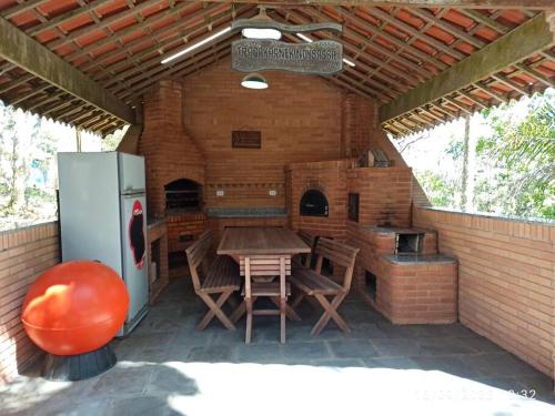 an outdoor kitchen with a table and a refrigerator at Casa de Campo em Serra da Cantareira in Mairiporã