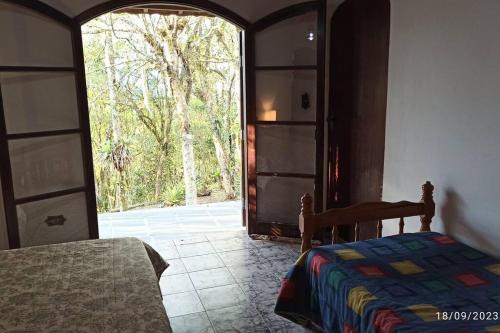 a bedroom with a bed and an open door at Casa de Campo em Serra da Cantareira in Mairiporã