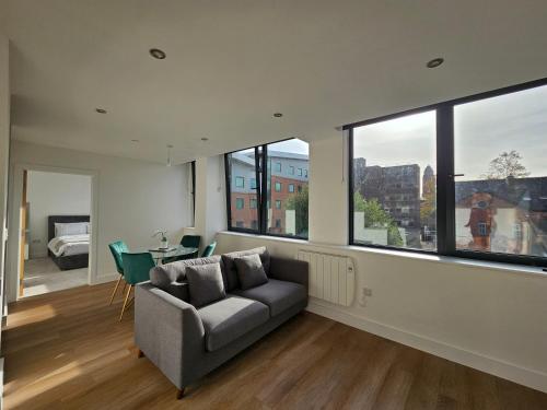 a living room with a couch and large windows at Brand New Trafford Apartment in Manchester