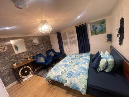 una camera con un letto blu e un divano di Spacious loft converted bedroom with toilet only, Separate guest shower on ground floor plus free parking a Hanworth