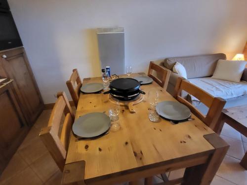 een houten eettafel met borden en glazen erop bij Ecrins A4, 2 bedroom apartment, central Samoëns in Samoëns