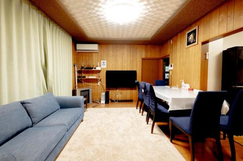 a living room with a couch and a table with chairs at HDO Furano Garden House in Furano