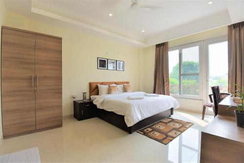 1 dormitorio con cama y ventana grande en Olive Service Apartments - Golf Course Road en Gurgaon