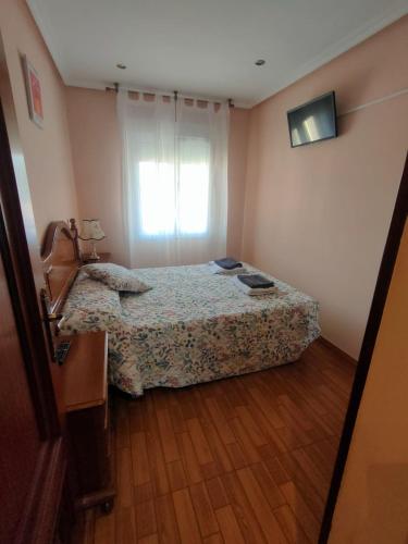 een kleine slaapkamer met een bed en een raam bij Piso Acogedor, en Zona Tranquila y a tan Solo 200 Metros de la Playa y el Centro in Candás