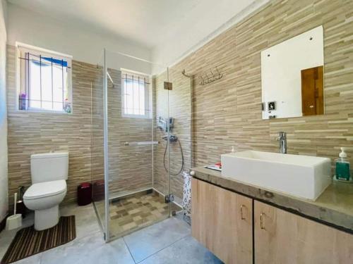 a bathroom with a toilet and a sink and a shower at Villa Cococherie in Poste Lafayette