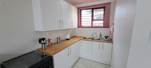 a kitchen with white cabinets and a wooden counter top at Cosy Carlisle in Port Elizabeth