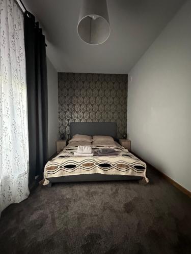 a bedroom with a bed and a large window at Apartament Oksford 1 in Okszów
