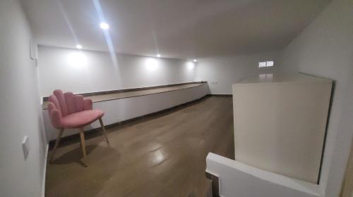 uma sala de espera com uma cadeira rosa num quarto vazio em Villa Urbina em Olerdola