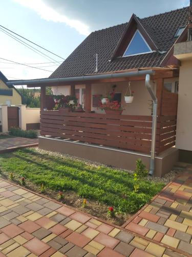 a house with a wooden fence with flowers on it at Panoráma Apartmanház in Abaújszántó