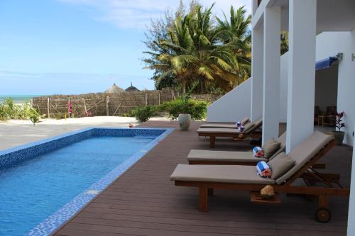a pool with chaise lounges next to a resort at Kivuli Beach Resort Paje in Paje
