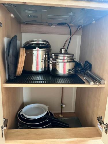 two pots and pans sitting on a shelf in a kitchen at Stacaravan Middelkerke in Middelkerke