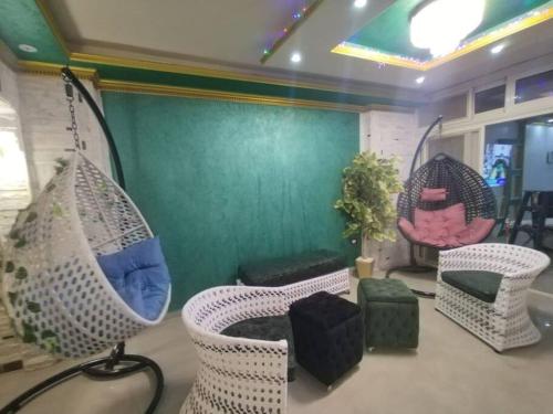 Habitación con sillas de mimbre y pared verde. en شقه فاخره على الكورنيش en Alexandría