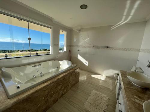 a bathroom with a tub and a sink and a window at CasAmarela in Santa Cruz Cabrália