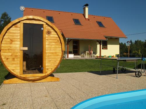 a large wooden barrel house with a table in front of a house at Chalupa Les Království in Souvrať