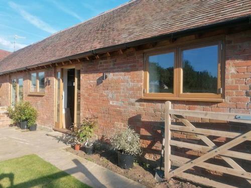 uma casa de tijolos com uma janela e uma cerca de madeira em The Old Dairy. A beautifully converted barn with stunning views em Charlecote