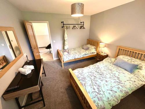 a bedroom with two beds and a desk and a mirror at Moonsticks, Modern & Well Presented 5 Bed House in Spixworth