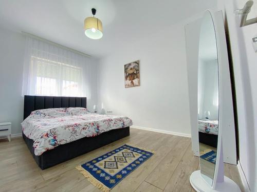 a white bedroom with a bed and a mirror at Klea’s Apartaments in Pristina
