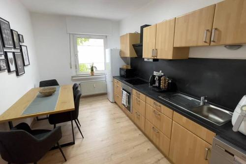 eine Küche mit Holzschränken, einem Tisch und einer Spüle in der Unterkunft Apartment FeWo54 FreeWifi, Free Parking, SmartTV in Hamm