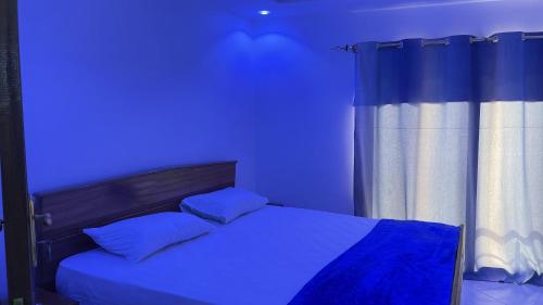 una camera blu con un letto con una luce blu di residence cheikh mahy cisse a Kaolack