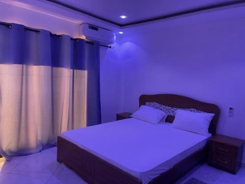 una camera da letto con letto e illuminazione viola di residence cheikh mahy cisse a Kaolack