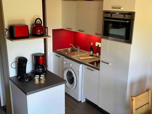 une petite cuisine avec un évier et une machine à laver dans l'établissement Cocon des chaumes, à La Bresse